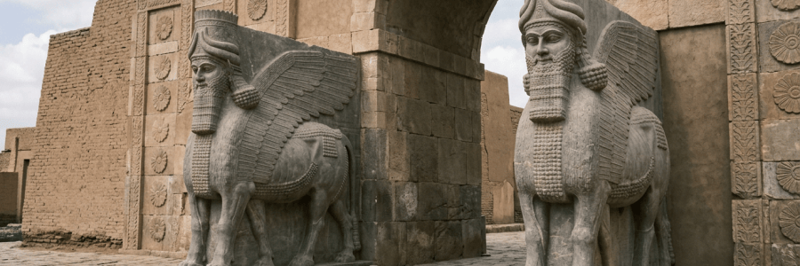 Two winged lamassu statues flanking an ancient stone arch